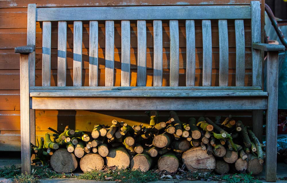 A wooden bench with cut logs beneath
