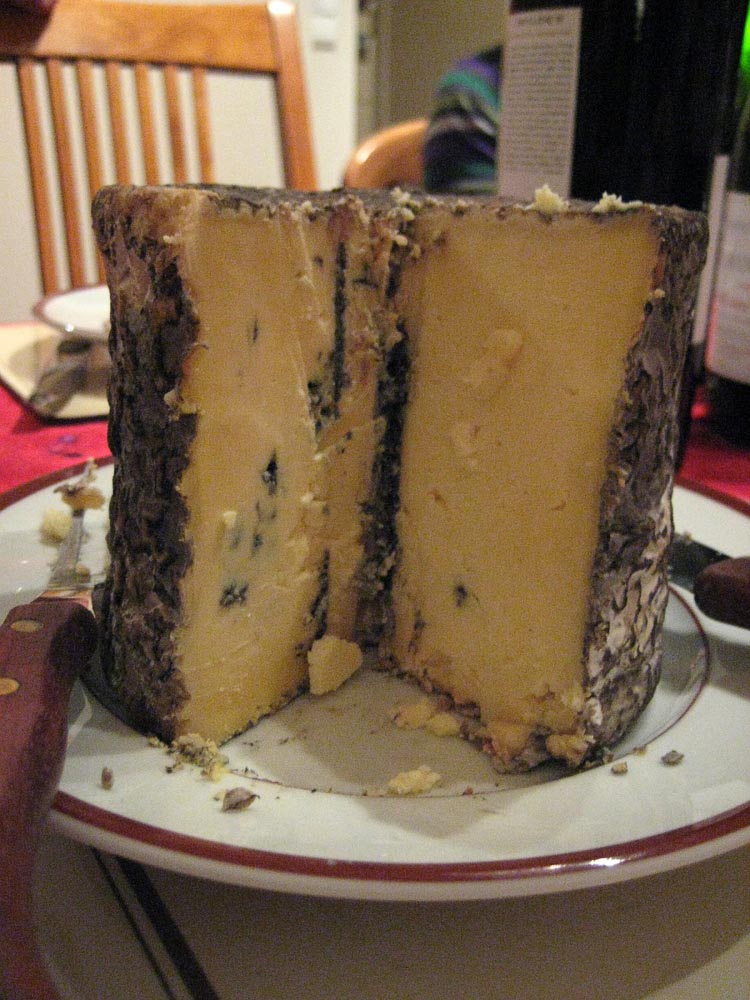 A whole blue cheese cut open to reveal the yellow cheese with blue mould inside.