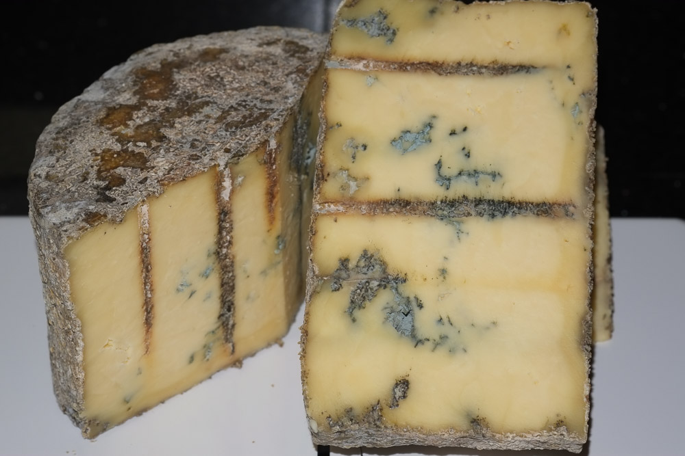 A blue cheese cut open revealing the yellow cheese with blue mould marbling.