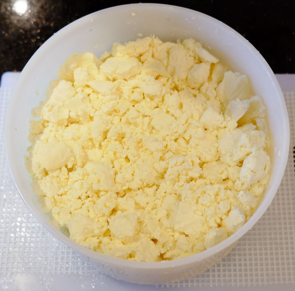 Cheese curds loosely packed into a white cylindrical mould