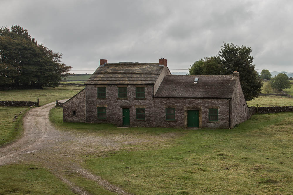 A house with a rough gravel track running up to and past it.