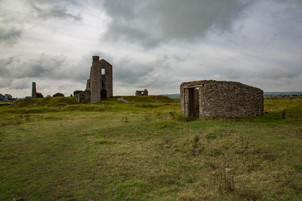 Mine working buildings showing the low powder house with chimneys and other buildings in the background