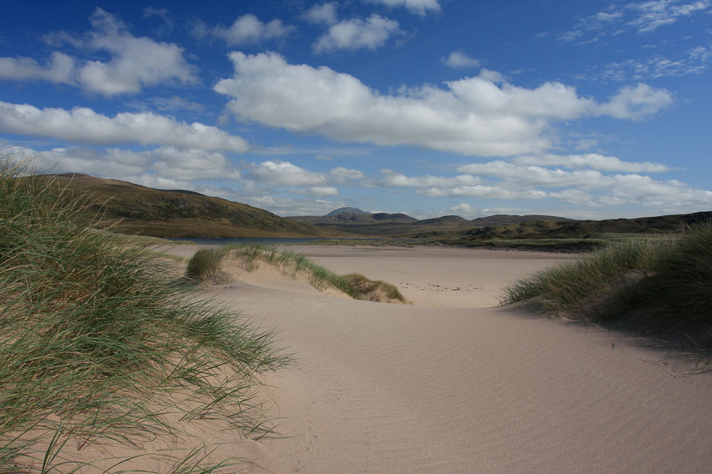 Image of sand dunes with grass and mountains and moorland in the distance
