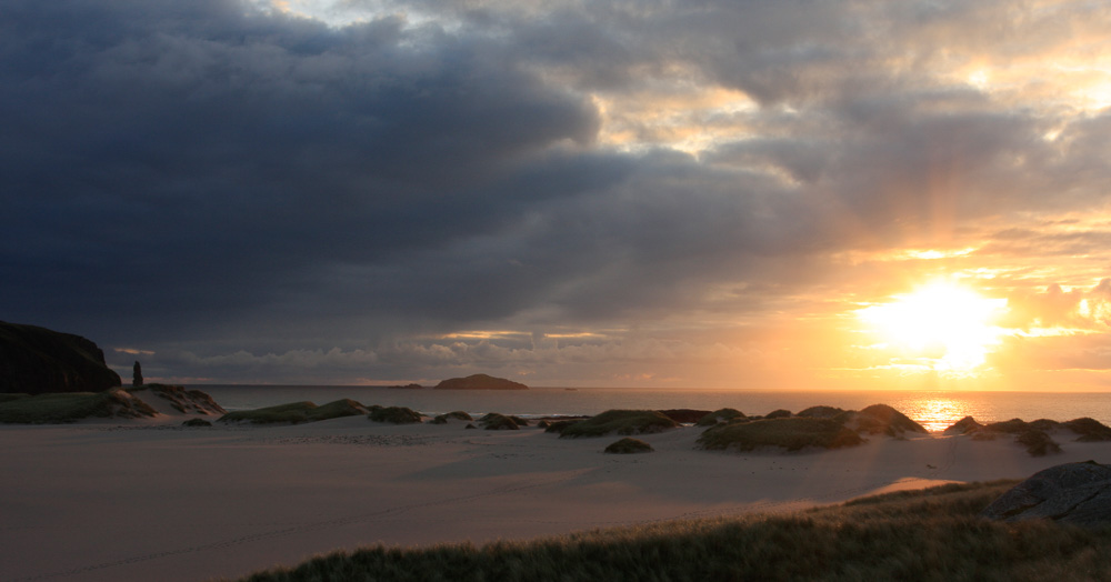 Image of the setting sun over sand dunes