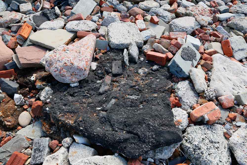 A piece of black tar like substance containing bricks and other material