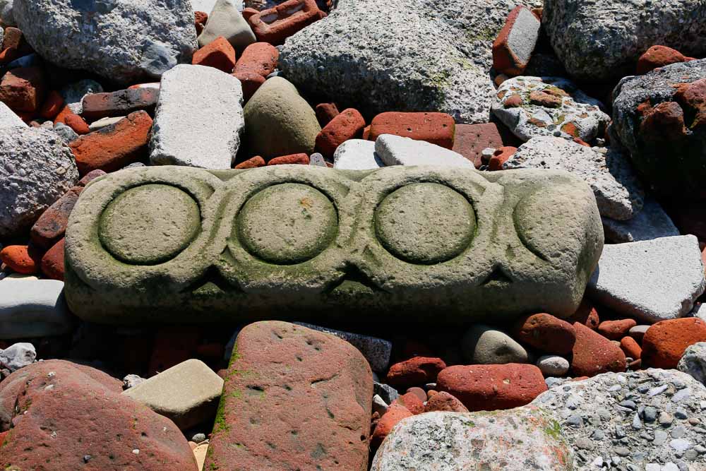 An oblong piece of carved sandstone with three circles carved into the surface
