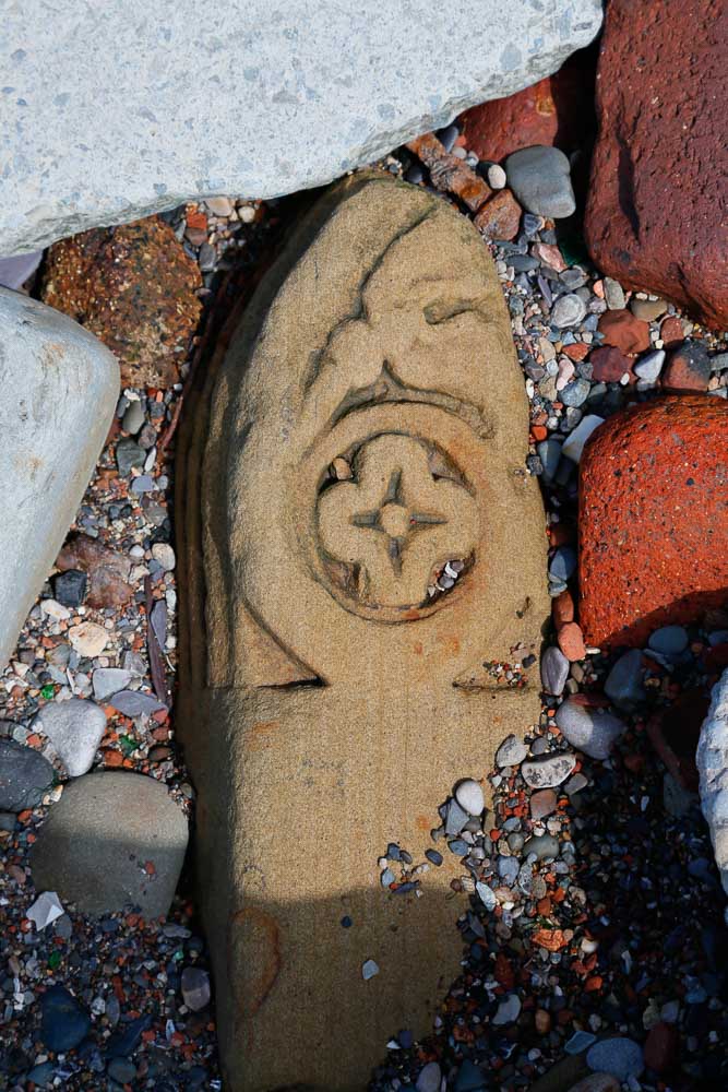 A large piece of carved sandstone with a rose of cross at the top